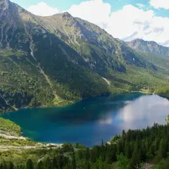 Widok na Morskie Oko, największe jezioro w Tatrach, otoczone stromymi, zalesionymi zboczami gór.