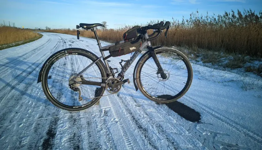 Rower Kross z zamontowanymi błotnikami na zaśnieżonej drodze. Idealny do jazdy w trudnych warunkach.