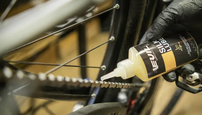 Rękawiczka z czarną rękawiczką aplikuje olej do łańcucha rowerowego. Jaki smar do łańcucha rowerowego wybrać? Ten "Silk Lube" wygląda obiecująco.