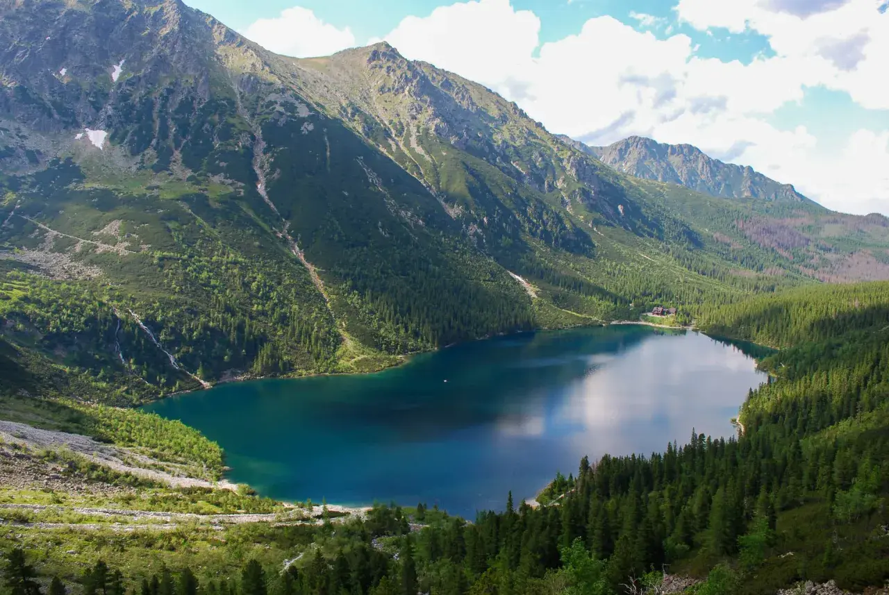 Widok na Morskie Oko, największe jezioro w Tatrach, otoczone stromymi, zalesionymi zboczami gór.
