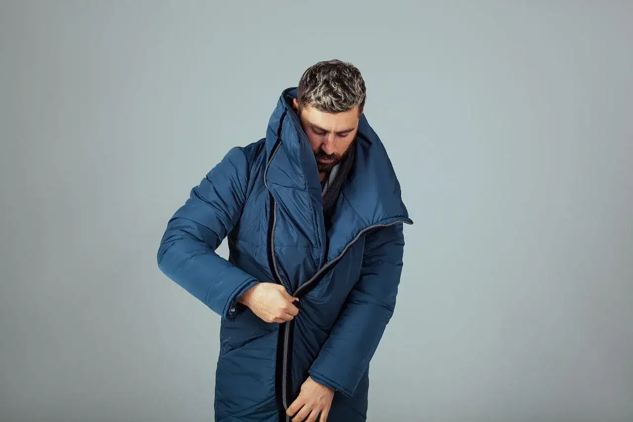 Mężczyzna zapina granatową kurtkę z dużym kołnierzem, która zapewnia doskonałe parametry gore tex.