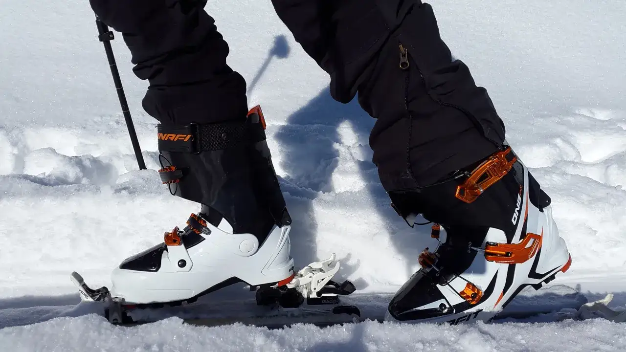 Skitury co to? Widok z perspektywy narciarza na buty i wiązania do skituringu w śniegu.