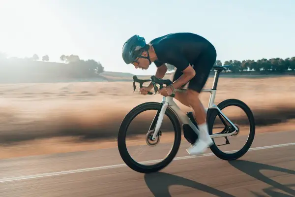 Kolarz w aerodynamicznej pozycji minimalizuje opory toczenia opon rowerowych, pędząc przez krajobraz.